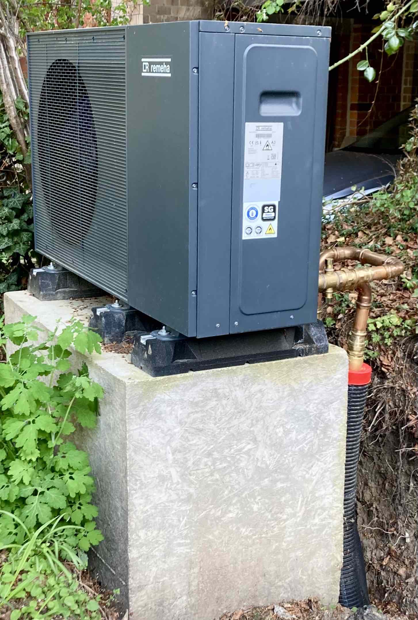 Außeneinheit einer Luft-Wasser-Wärmepumpe neben einem Wohnhaus